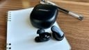 black bose earbuds on white notebook with pen