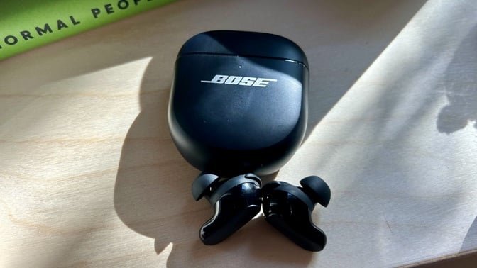 black bose qc ultra 2 earbuds on shelf next to books